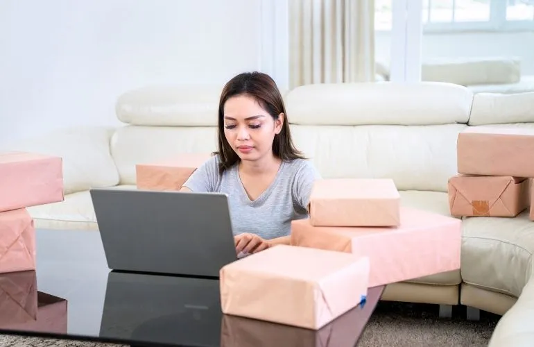 Asian woman doing startup online business while working with laptop in the living room at home